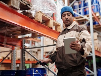 a man holding a tablet checks inventory at a logistics warehouse